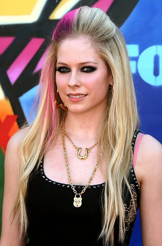 Avril Lavigne shows off her "Drink Me" necklace while running her fingers